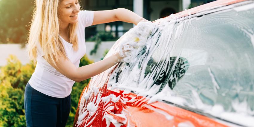 Woman washes her car and performs preventative vehicle maintenance for spring