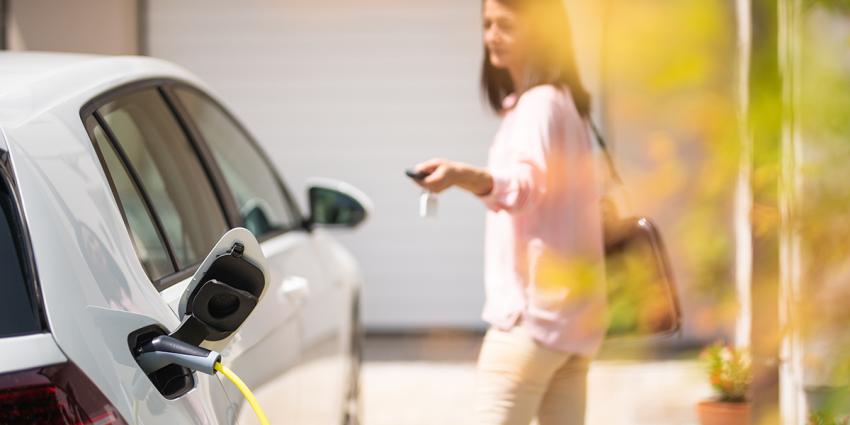 Do electric vehicles use oil? A woman locks her car while it charges.