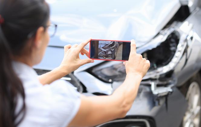 Woman takes a picture of vehicle damage after an accident for car insurance
