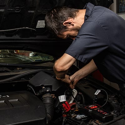 Auto repair technician works under a vehicle's hood in Clarendon