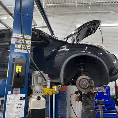 Auto repair technician works underneath a vehicle in Alexandria
