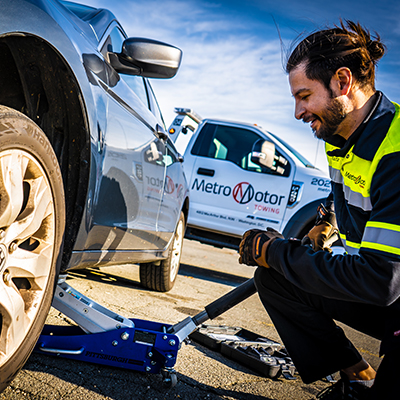 Tow truck driver repairs a flat tire during roadside assistance