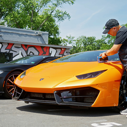 A Metro Motor technician color matches the orange paint on a luxury vehicle
