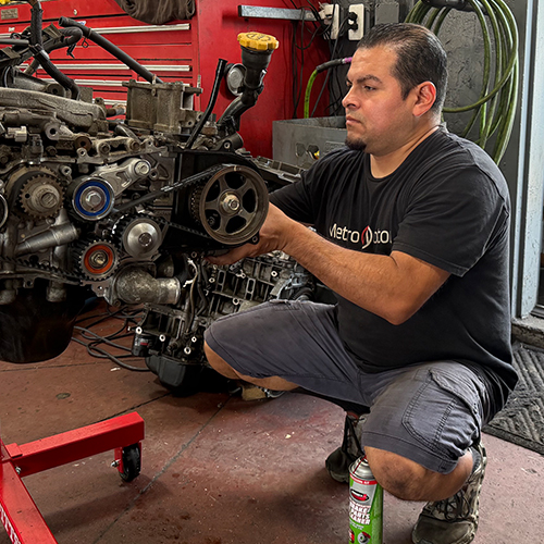 An engine technician works on an engine in the Arlington auto repair shop