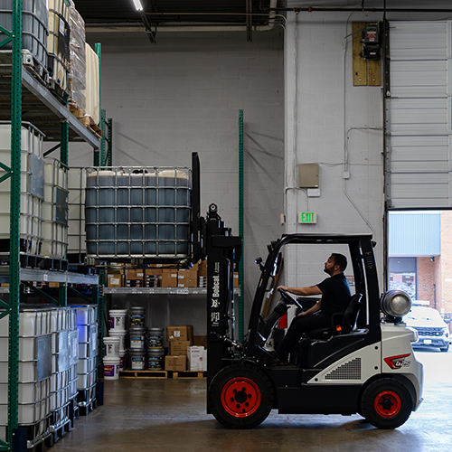 Forklift driver at Metro Motor Auto Supply stacks bulk oil containers