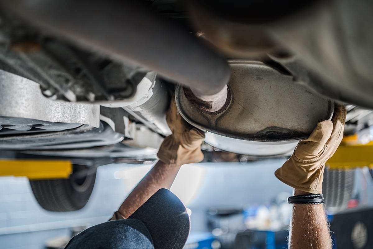 An automotive technician inspects a vehicle's exhaust system