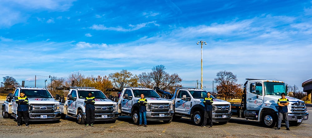 Metro Motor towing service operators stand in front of a row of tow trucks