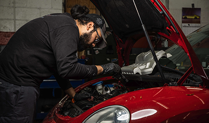 Mechanic inspects under a vehicle's hood in an auto repair shop in DC.