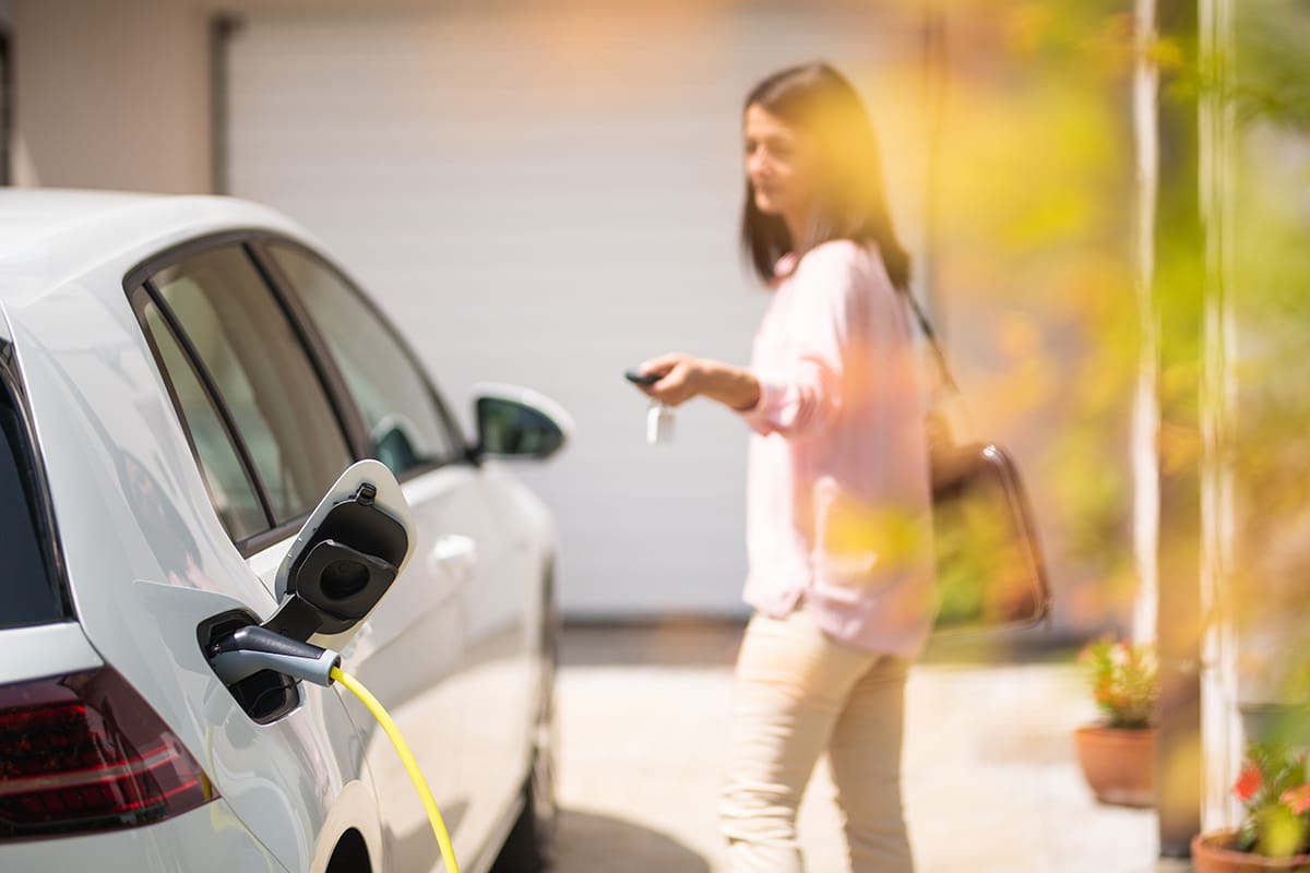 Do electric vehicles use oil? A woman locks her car while it charges.