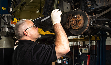 Auto repair technician inspects a vehicle's brakes in a local mechanic shop