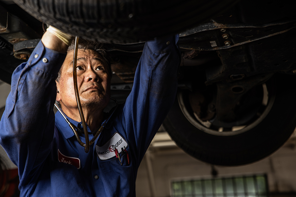 Image: A Metro Motor automotive technician inspects the underside of a vehicle.