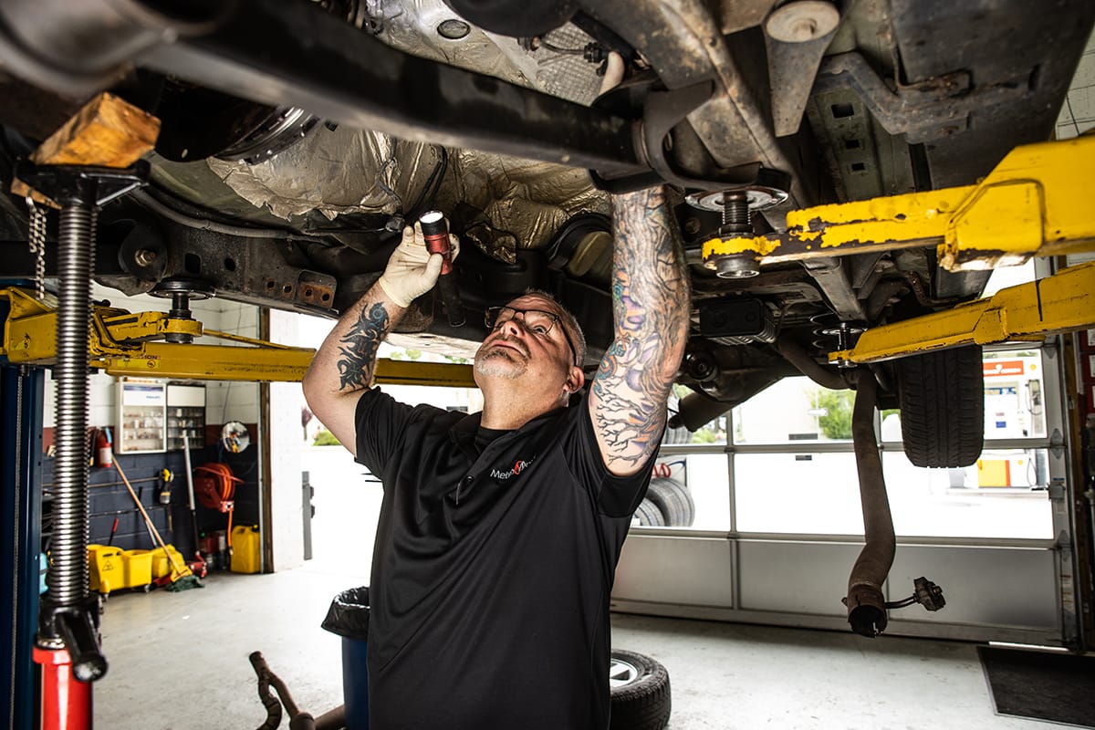 Metro Motor technician inspects underside of vehicle at auto repair shop in Washington DC