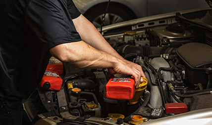Auto repair technician performs an oil change on a vehicle in an auto repair shop.