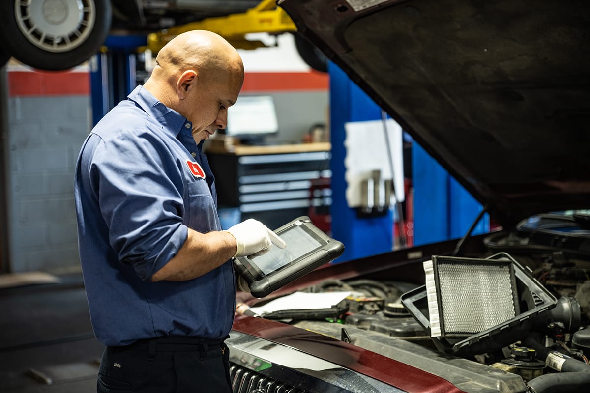 An auto repair technician uses an iPad to scan and diagnose needed vehicle repairs