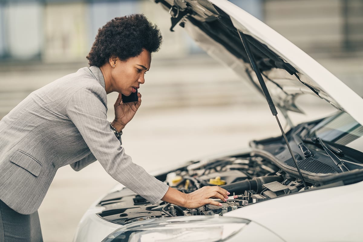 Woman inspects engine after hearing strange noises under the hood