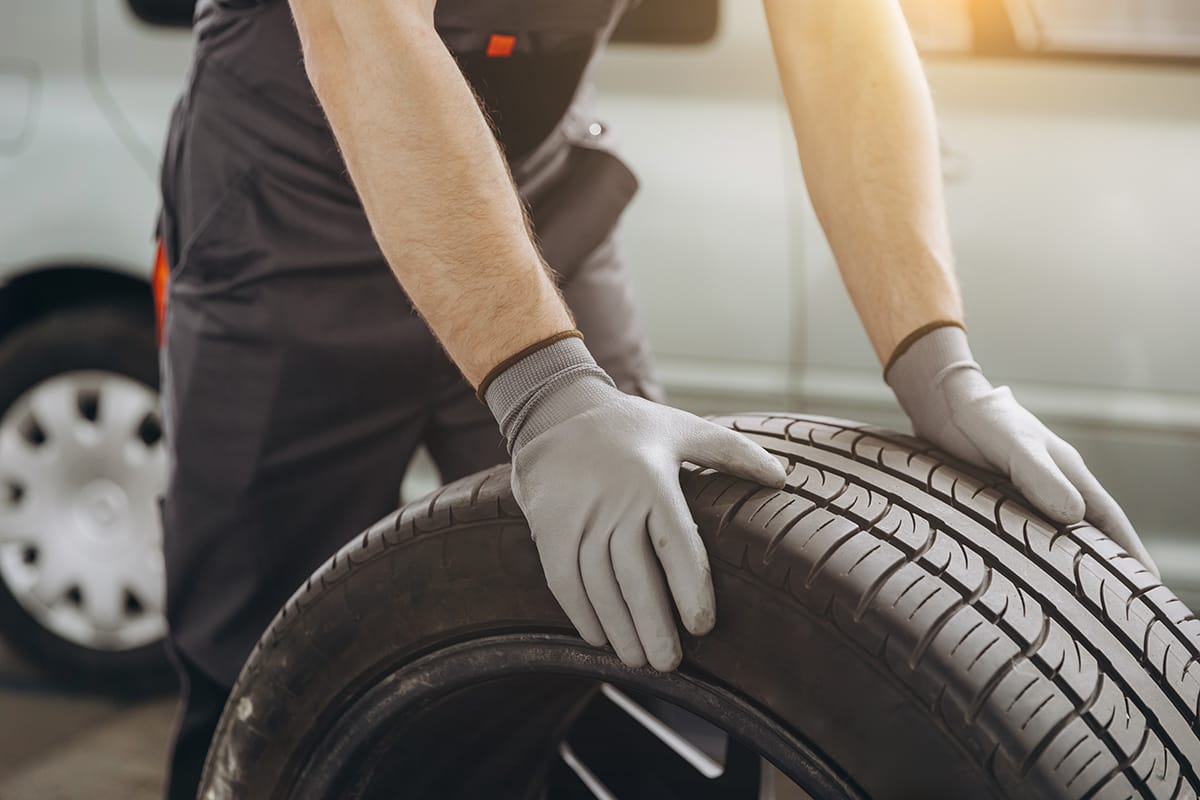Auto repair technician rolls a single tire in an auto repair shop