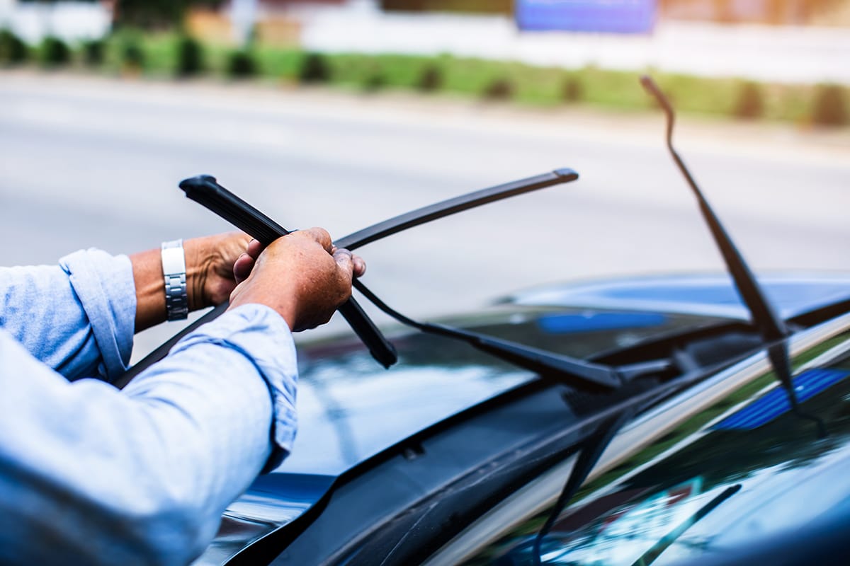 Man replaces windshield wipers on a vehicle.