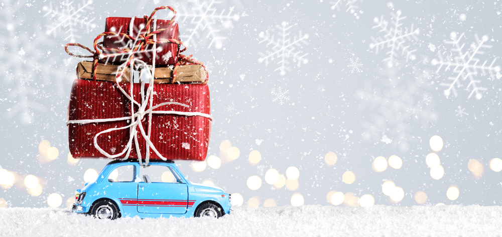 Small blue toy car with large Christmas presents tied to the roof