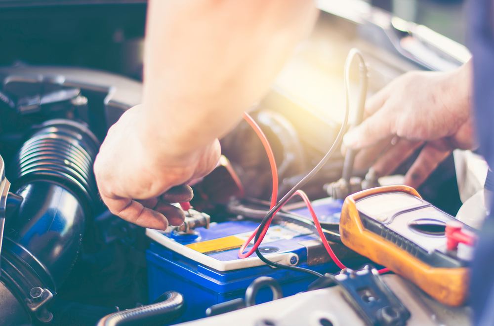 Close up on out-of-frame mechanic working on a car battery 