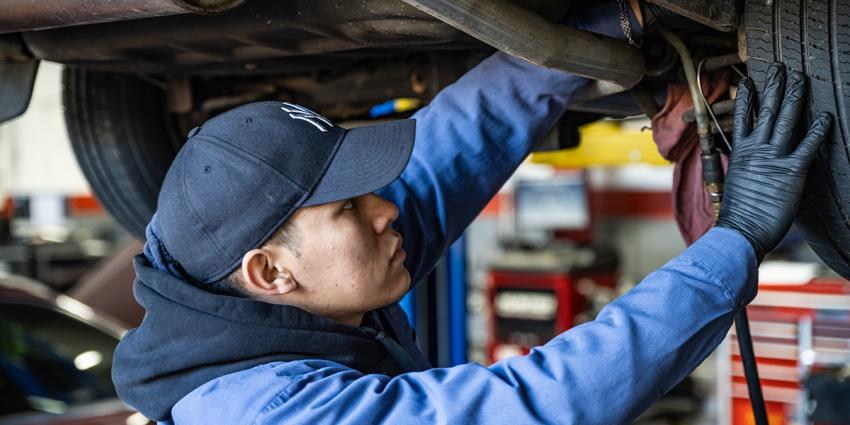 A Metro Motor technician inspects under a vehicle at an auto repair center in D.C.