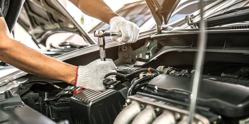 Auto mechanic in DC works on an engine