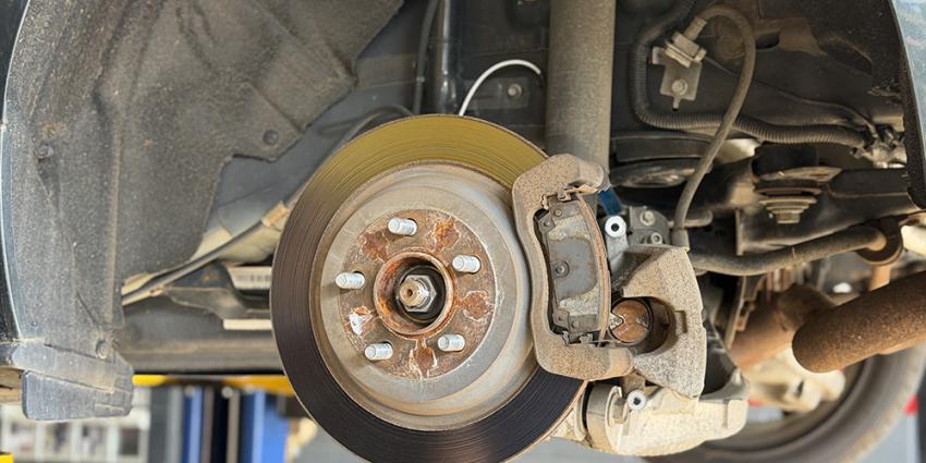 Detail of a vehicle's brake pads and rotor in a Metro Motor auto repair shop