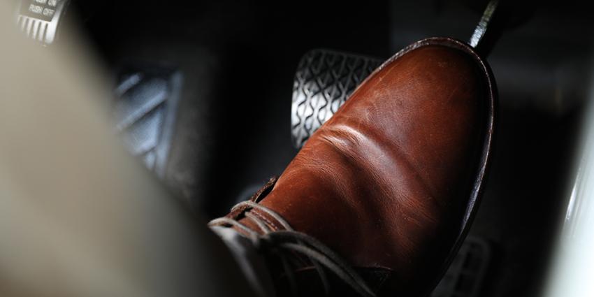 Man's shoe pressing down on car brake pedal
