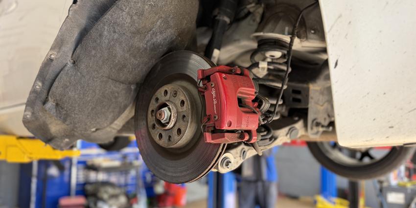 A vehicle on a lift with exposed brakes at a Metro Motor auto repair shop