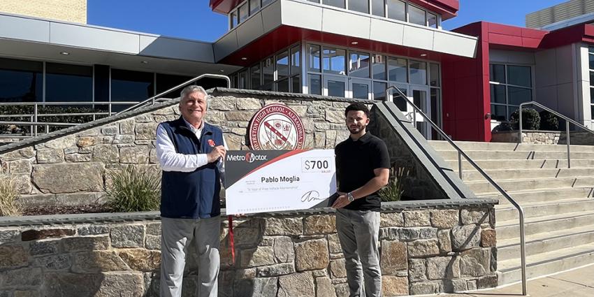 Metro Motor team member presents check to teacher in front of school
