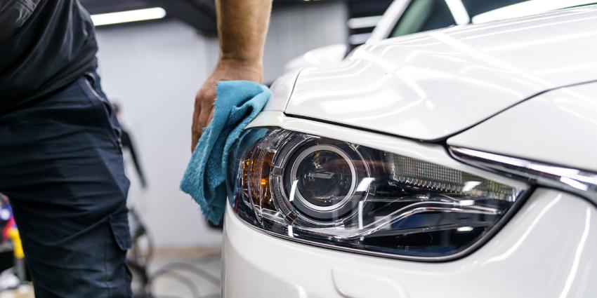 Paint repair technician buffs a white vehicle after removing a scratch