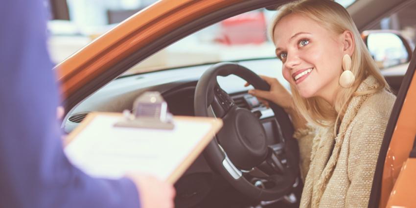 Woman looks up at auto mechanic from the front seat of her car in the auto shop