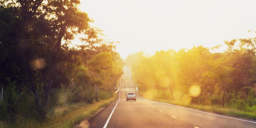 Lone car on a back roads high way, illuminated by a warm sunset